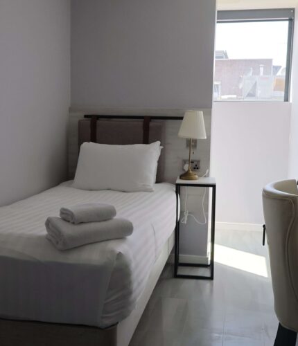 Cosy single room with bed, desk, and city view; features modern decor and ample natural light for a relaxing stay.